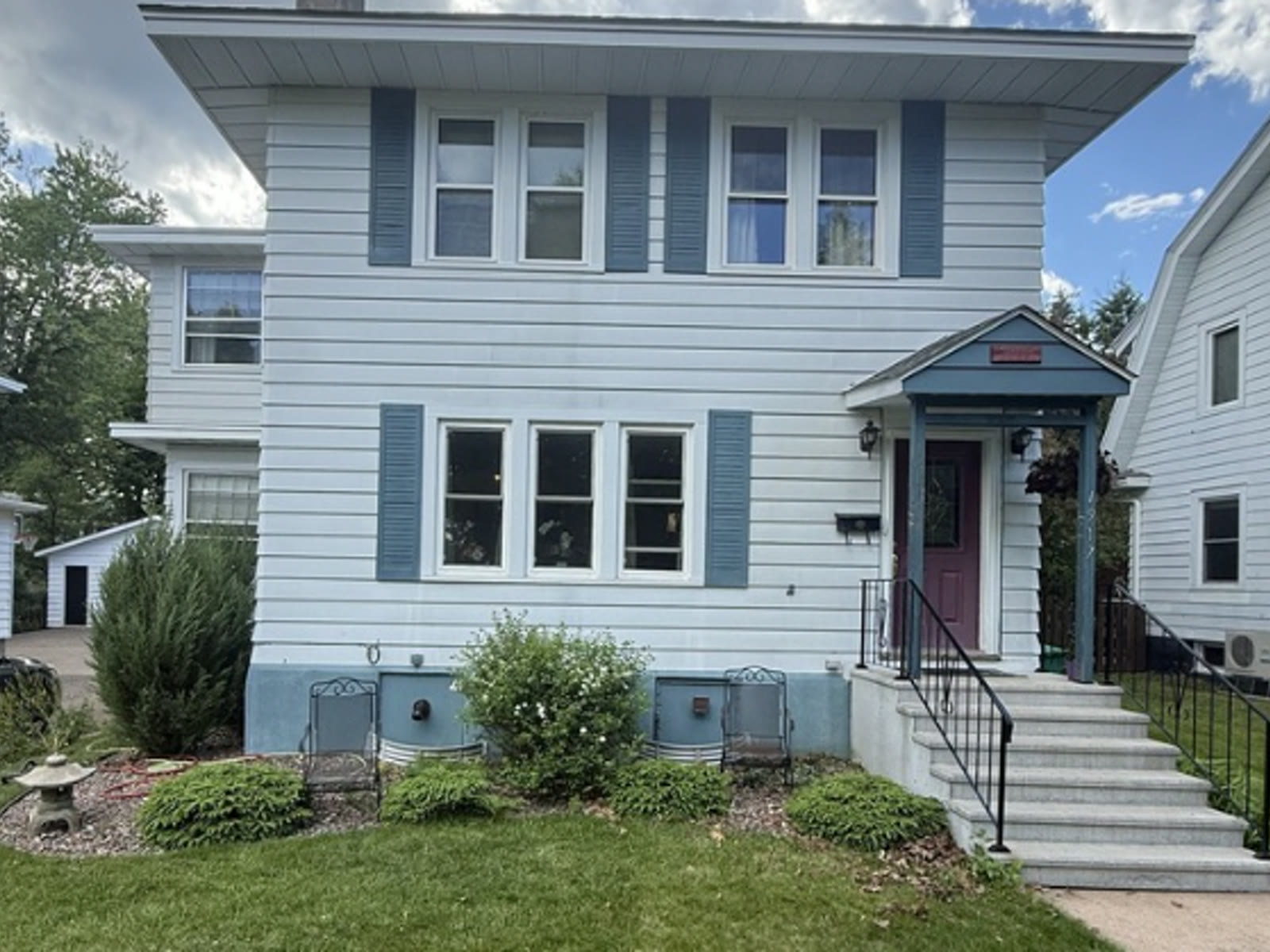 Before: light blue two-story home with blue shutters and burgundy front door