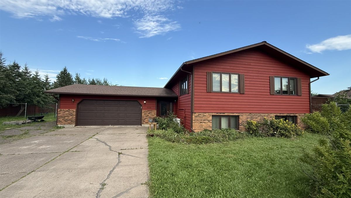 Exterior painting on a split-level home with bold red siding