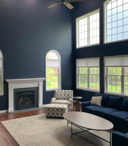 Interior painting with navy walls and crisp white trim in a modern living room